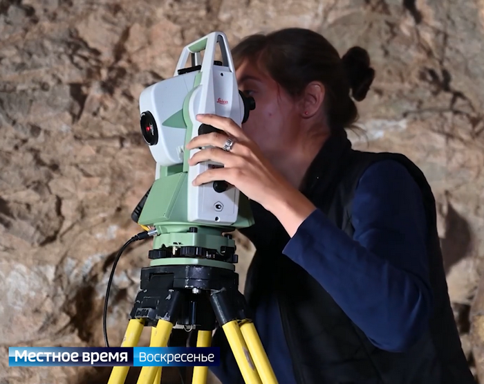 Археолог в пещере с нивелиром