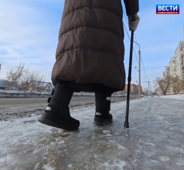 Пожилая женщина с тростью идёт по обледеневшему тротуару Пожилая женщина с тростью идёт по обледеневшему тротуару