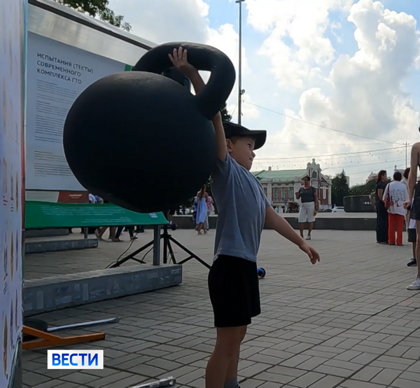 Мальчик поднимает огромную гирю