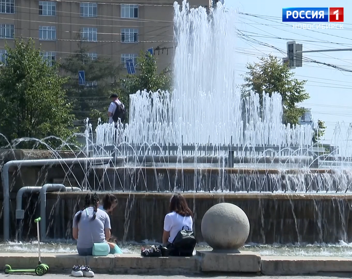 Люди спасаются от жара у фонтана 