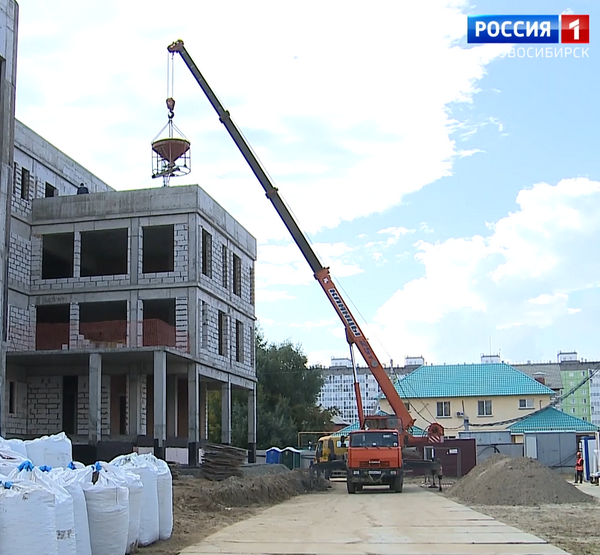 Автокран на стройплощадке поднимает груз 