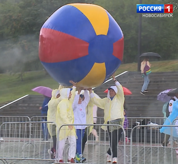 Команда несёт огромный мяч над головами