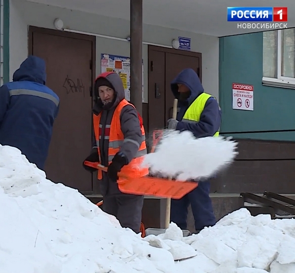 Дворники убирают снег около дома