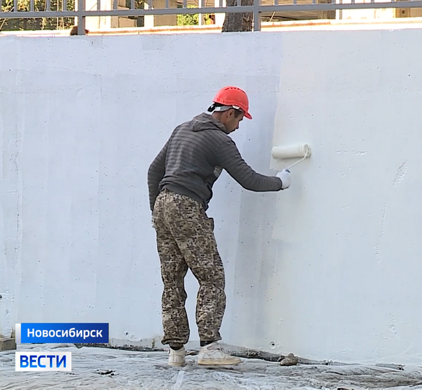 Рабочий красит стену